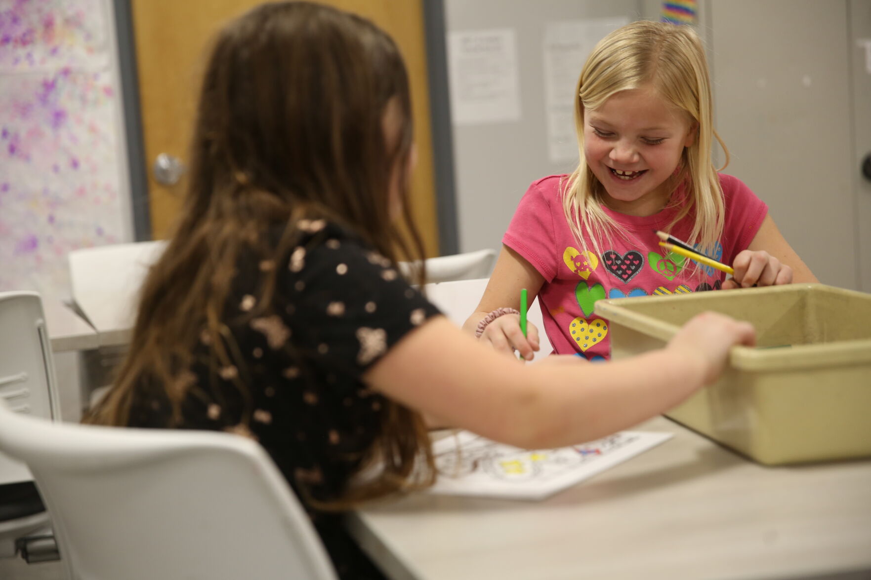 Oakley Garton, right, laughs while she uses colored pencils